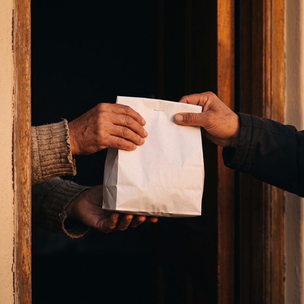 A pharmacist handing a sealed prescription bag across the counter